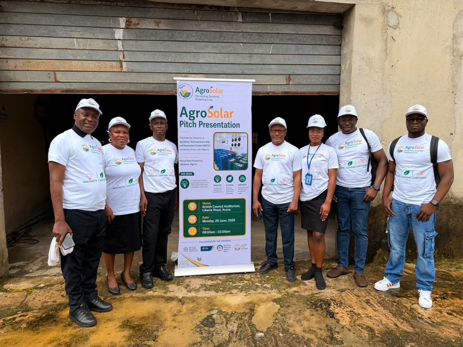 Seven AgroSolar team members standing beside an AgroSolar pitch presentation banner at a project site