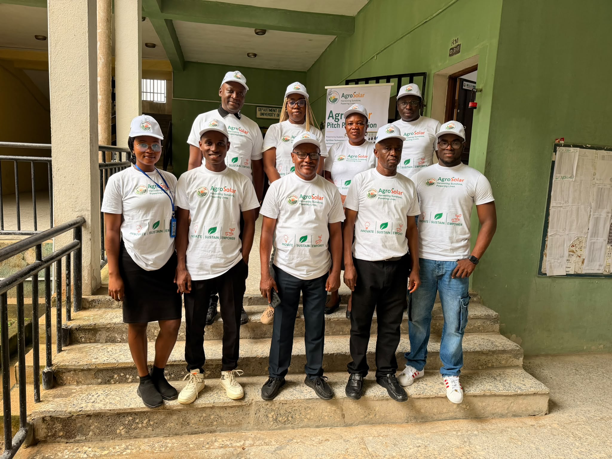 AgroSolar team members in branded T-shirts posing on the steps of a University of Uyo building during a site tour